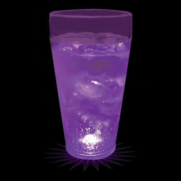 A 20 oz. plastic cup with a purple LED light filled with purple liquid on a bar counter.