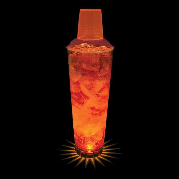 A customizable plastic cocktail shaker with orange LED lights on a glass of orange liquid.