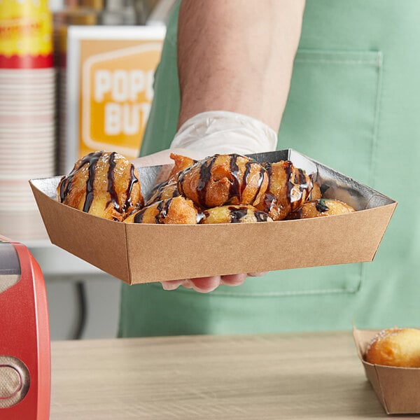 A person holding a tray of food in a Carnival King box.