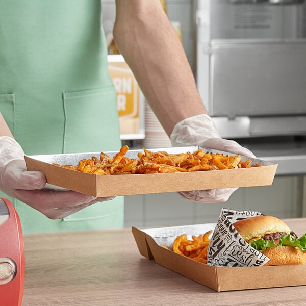 A person holding a Carnival King paper food tray of french fries.