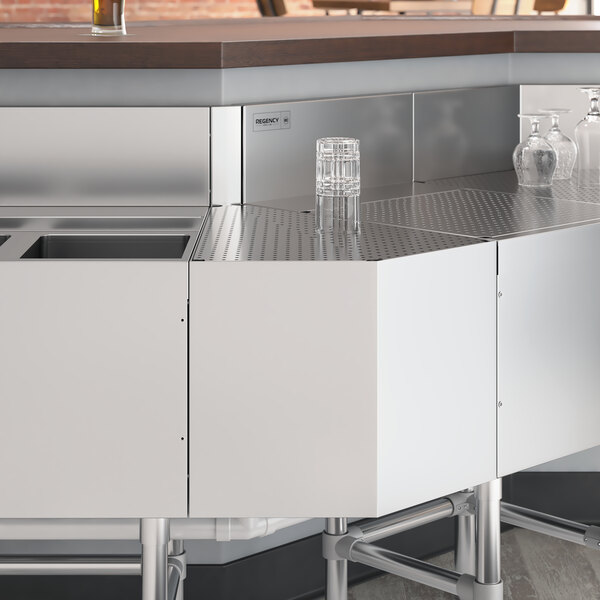 A Regency stainless steel 45-degree angle outside corner underbar filler on a counter in a professional kitchen.