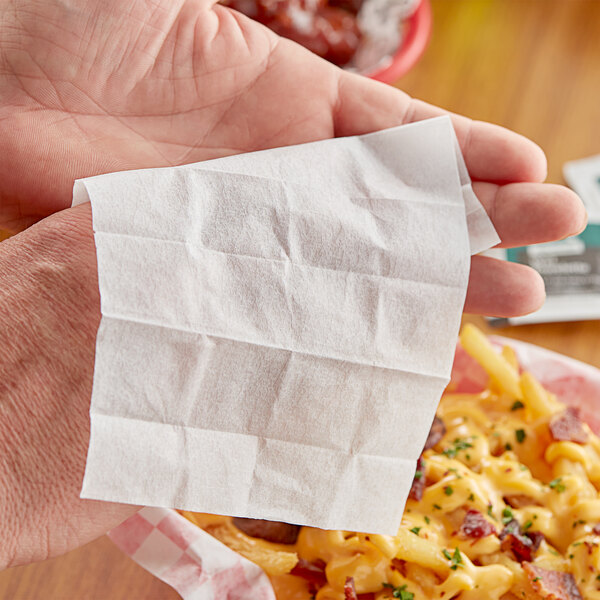 A hand holding a Choice 70% Alcohol Antiseptic Moist Towelette over a plate of food.