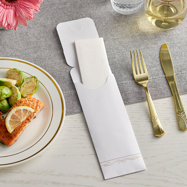 A white paper cutlery caddy on a table with a plate of food, a napkin, and a fork.