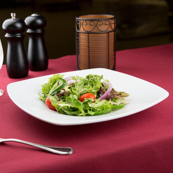 A CAC Super White Porcelain square salad plate with salad on a table.