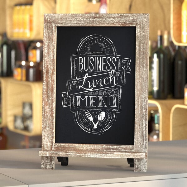 A Flash Furniture Canterbury weathered chalkboard with metal scrolled legs on a wood shelf with a business lunch sign.