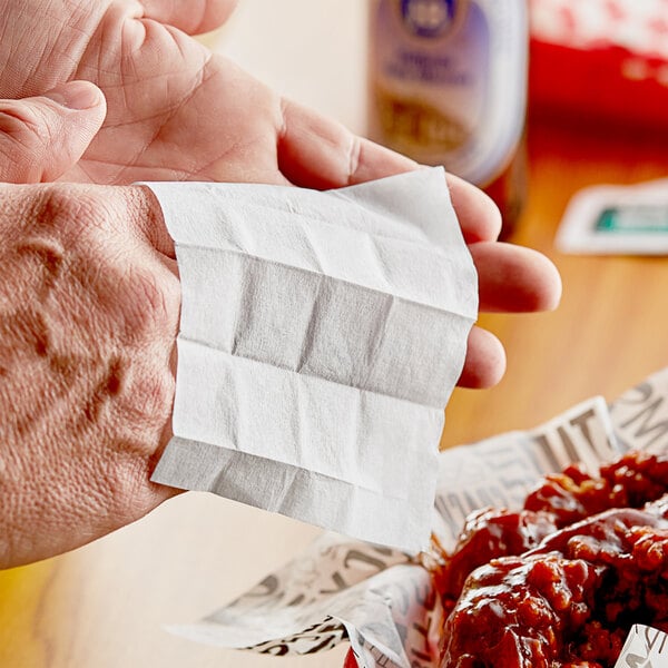 A person using a Choice lemon scented moist towelette to clean their hands at a table with food.