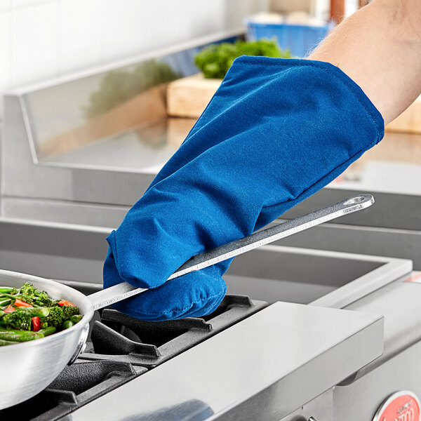 A person wearing a blue Tucker Safety Products Burnguard oven mitt holding a pan of vegetables.