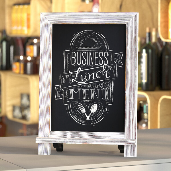 A whitewashed magnetic chalkboard with metal scrolled legs on a counter with "Business Lunch Menu" written on it.