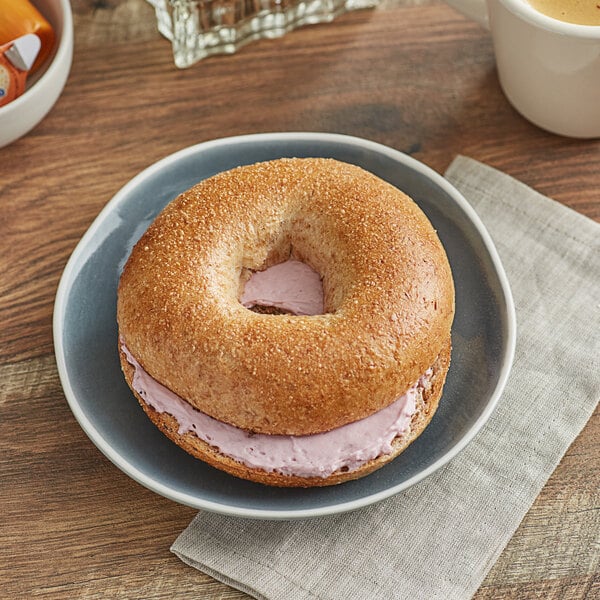 A honey wheat bagel with cream cheese on a plate.