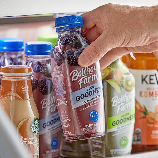 A close-up of a hand holding a small plastic bottle of Bolthouse Farms Blue Goodness Smoothie.