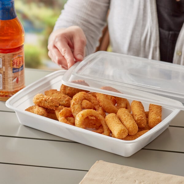 A woman holding a rectangular white Choice microwavable container with fried food inside.