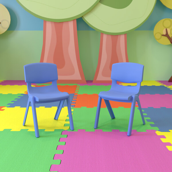 A pair of blue Flash Furniture Whitney plastic chairs on a colorful floor.