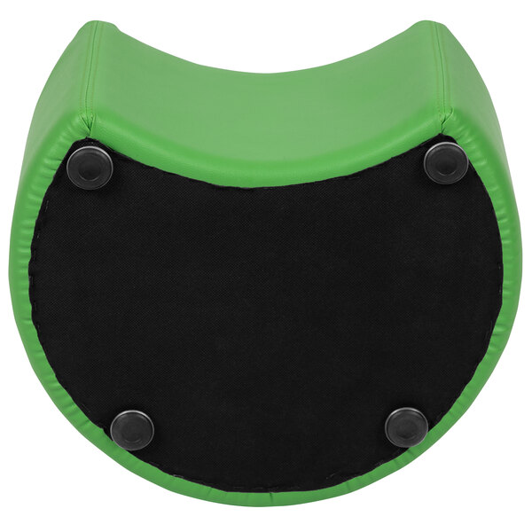 A green flexible moon seating ottoman with a black circle on the surface.