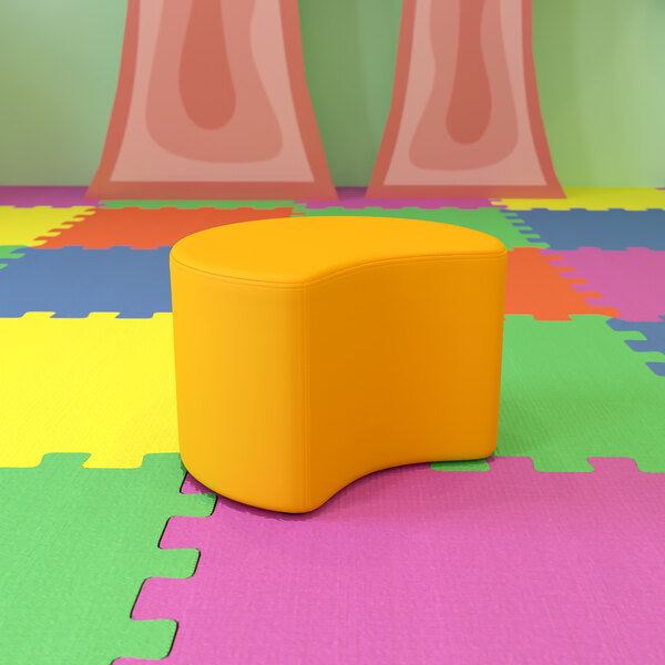A yellow Flash Furniture Nicholas flexible moon ottoman on a colorful surface.