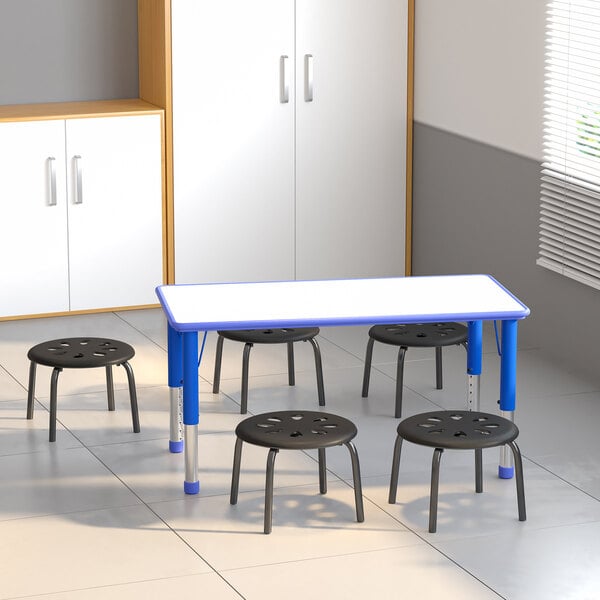 A group of Flash Furniture black plastic stackable stools under a table.