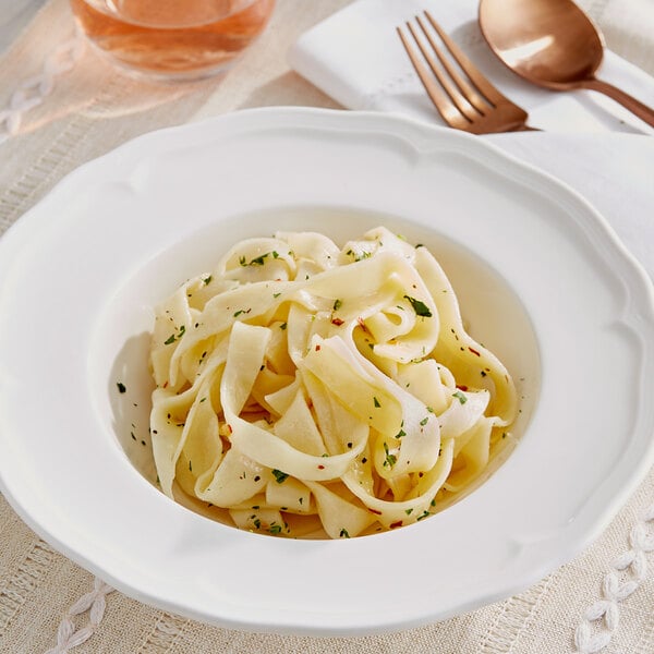 A white bowl of pasta with a fork.