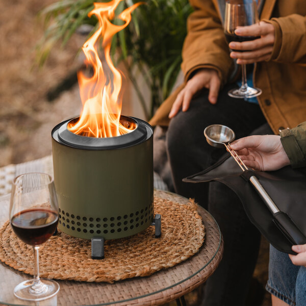 A Solo Stove Mesa XL fire pit on a table with a fire burning inside.
