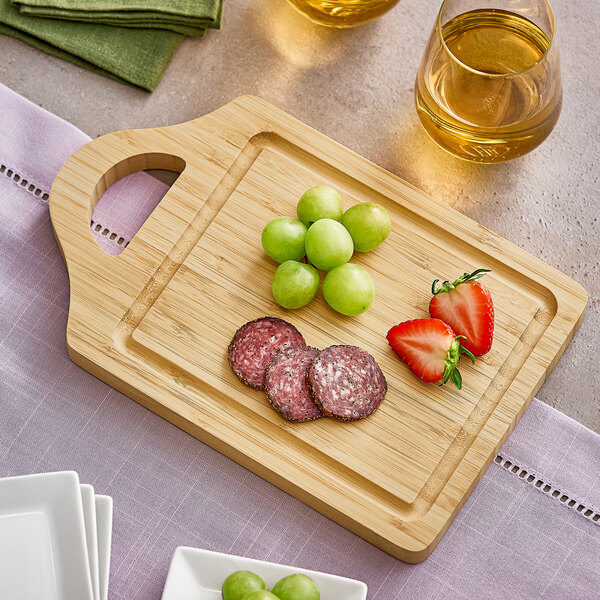 A Franmara bamboo cutting board with green grapes and fruit on a wooden surface.