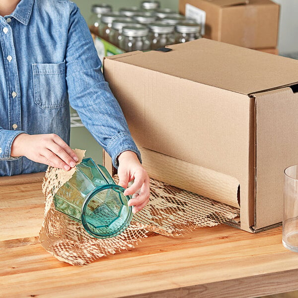 A woman using HexcelWrap MiniPack to wrap a glass jar.