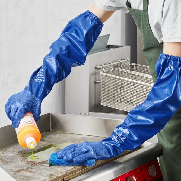 A person wearing blue Showa Nitrile gloves cleaning a surface.