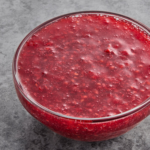 A glass bowl filled with diced red raspberries.