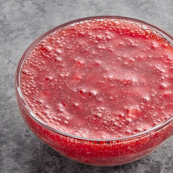 A glass bowl of Oregon Fruit diced strawberries in red liquid.