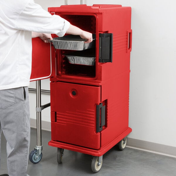 A man opening a Cambro red Ultra Camcart food container.