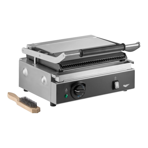A commercial panini grill with grooved cast iron plates and a cleaning brush.