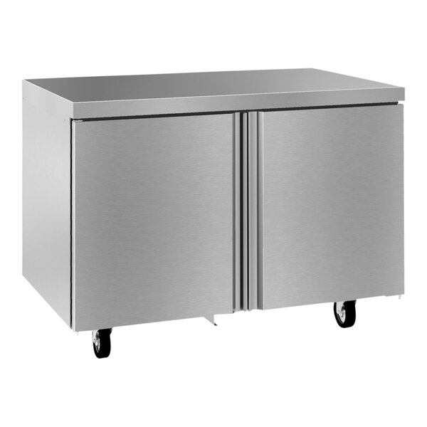 A silver metal Delfield undercounter refrigerator with wheels.