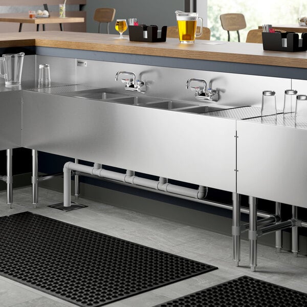 A Regency stainless steel underbar sink with drainboards and faucets.