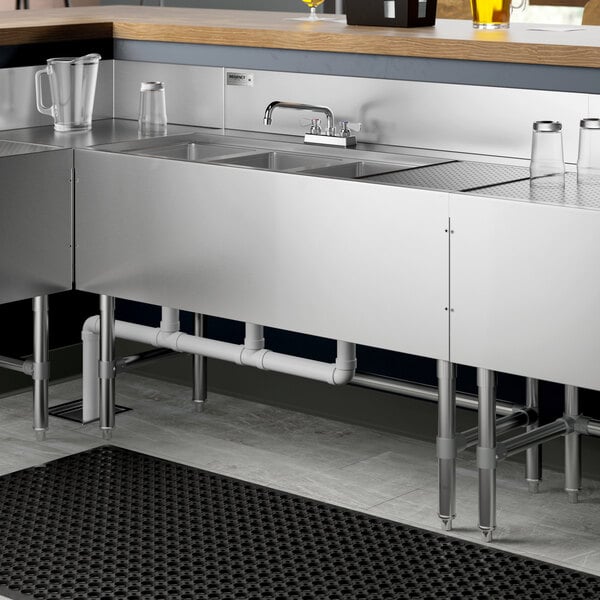 A Regency stainless steel underbar sink with three bowls, a right drainboard, and a faucet.