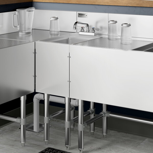 A Regency stainless steel underbar hand sink with a faucet on a black and white counter.