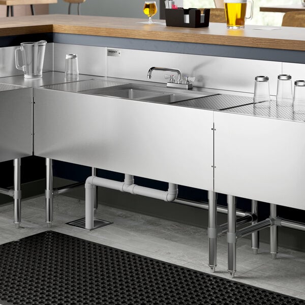 A Regency stainless steel underbar sink with (2) drainboards on a counter in a professional kitchen.