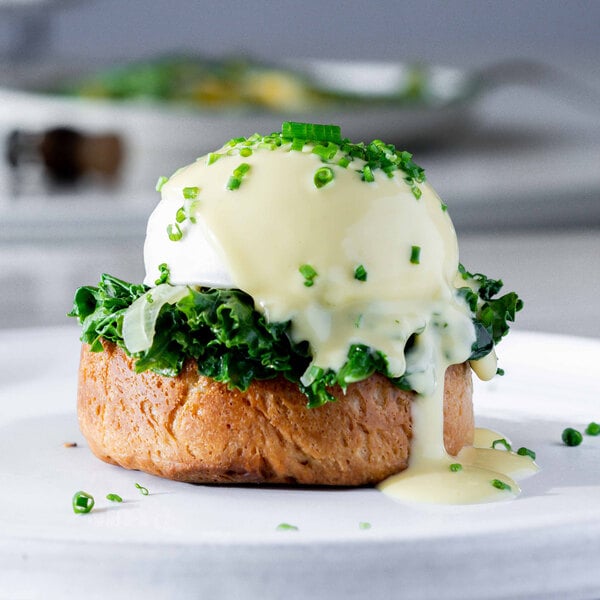 A plate topped with a Yo Egg Plant-Based Poached Egg and green onions on a table.