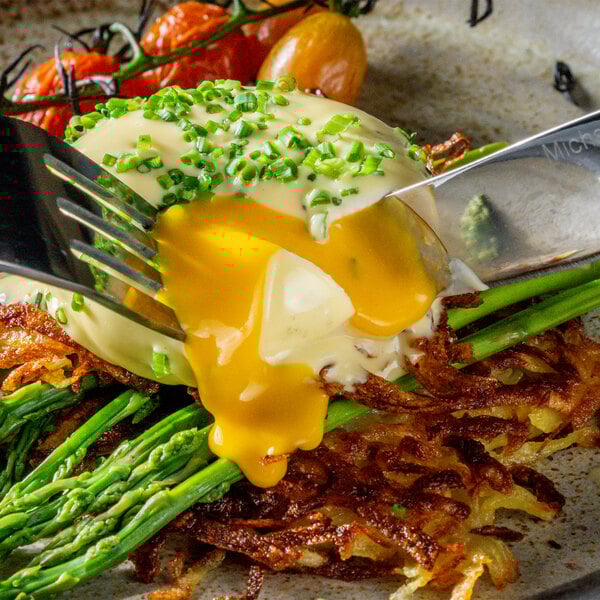 A fork holding a piece of food with asparagus and Yo Egg Plant-Based Poached Egg.