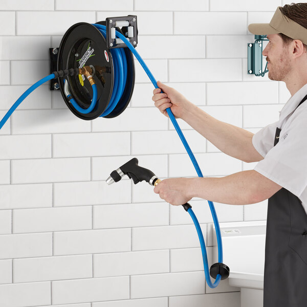 A man using a Regency hose reel to spray water.