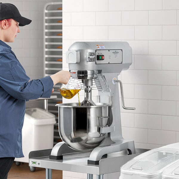 A woman pouring oil into a Main Street Equipment commercial mixer.