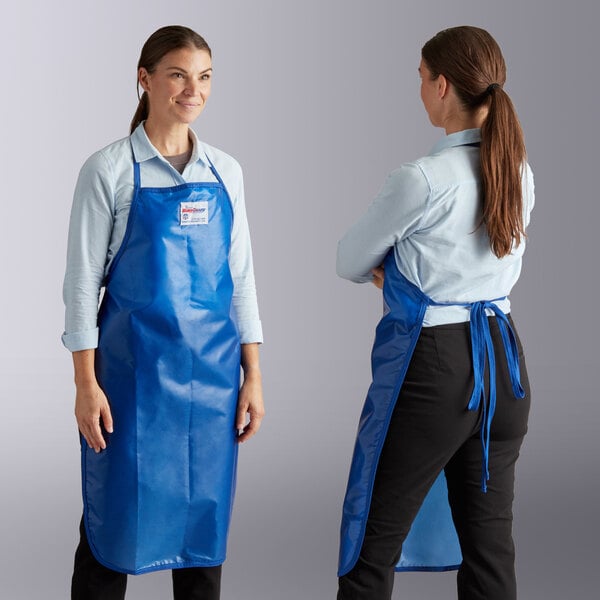 Two women and a person wearing blue Tucker Safety aprons in a professional kitchen.