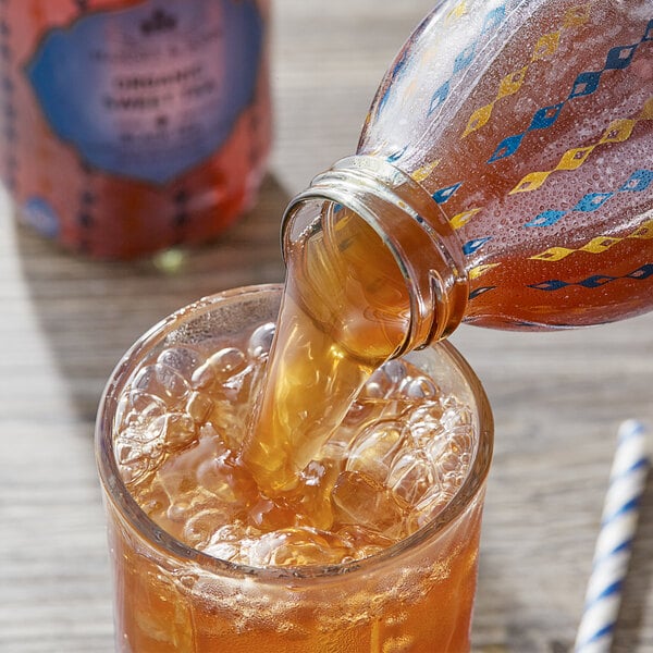 A Harney & Sons glass bottle pouring black liquid into a glass.