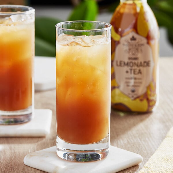 A glass of iced tea and a bottle of Harvey & Sons Organic Lemonade and Tea Juice Drink on a wooden tray.