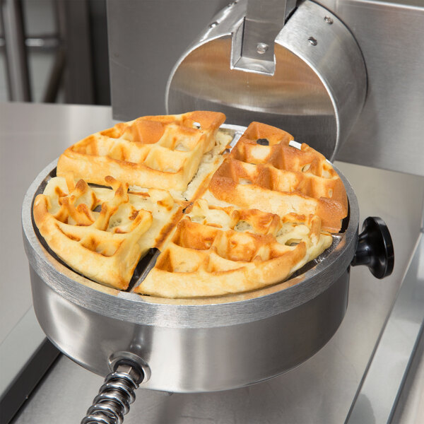 A Nemco commercial waffle maker with cooked waffles in it.