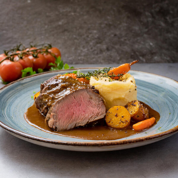 A plate of food with vegetables and meat covered in Au Jus.