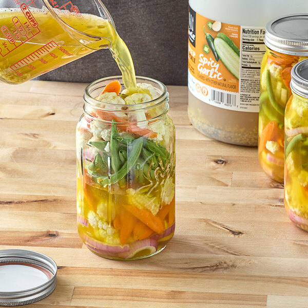 Foothill Farms Spicy Garlic Pickle Brine being poured into a jar of vegetables.