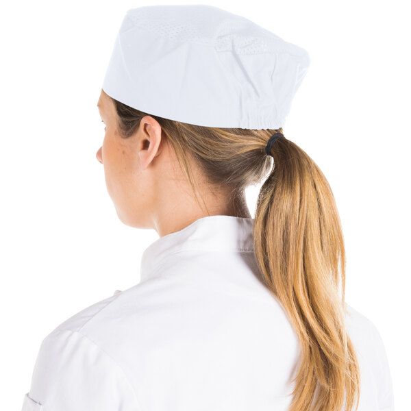 A woman wearing a white Chef Revival baker's skull cap with a mesh top.