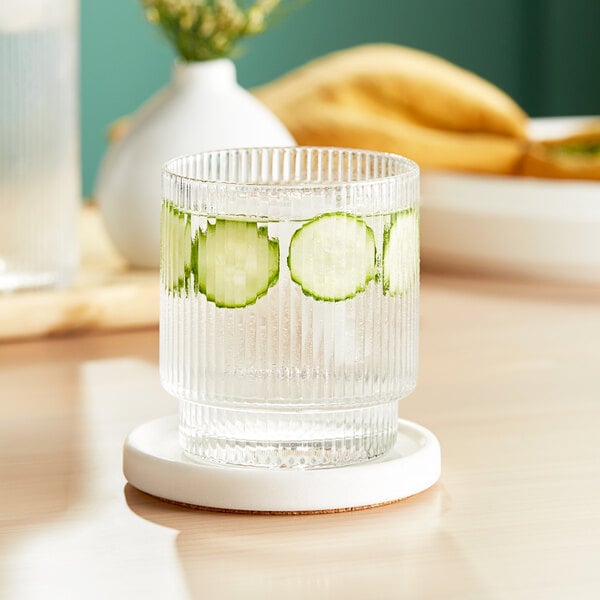 An Acopa Lore rocks glass of water with cucumber slices in it.