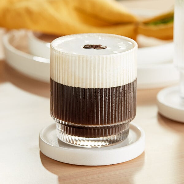 An Acopa Lore rocks glass filled with a drink on a coaster.