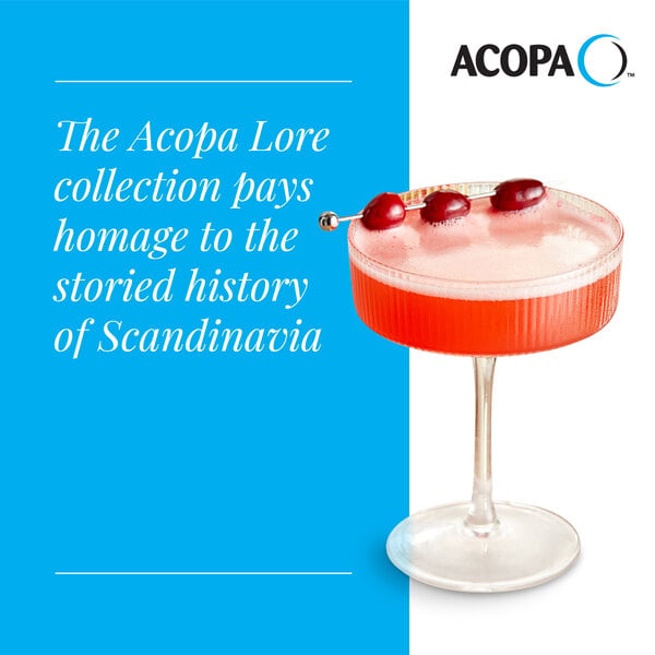 A clear coupe glass filled with a red cocktail and garnished with three cherries on a pick.