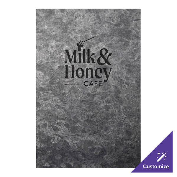 A close-up of a H. Risch, Inc. brushed metallic menu cover on a table in a café.