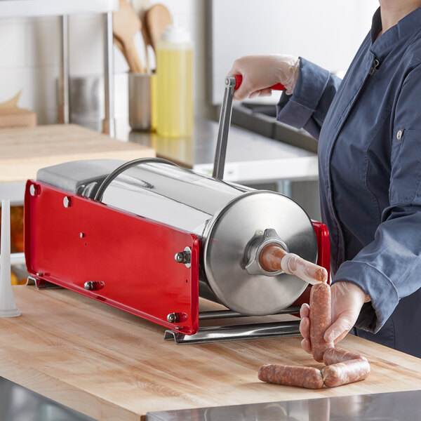 A woman using a Tre Spade manual sausage stuffer to fill a tube.