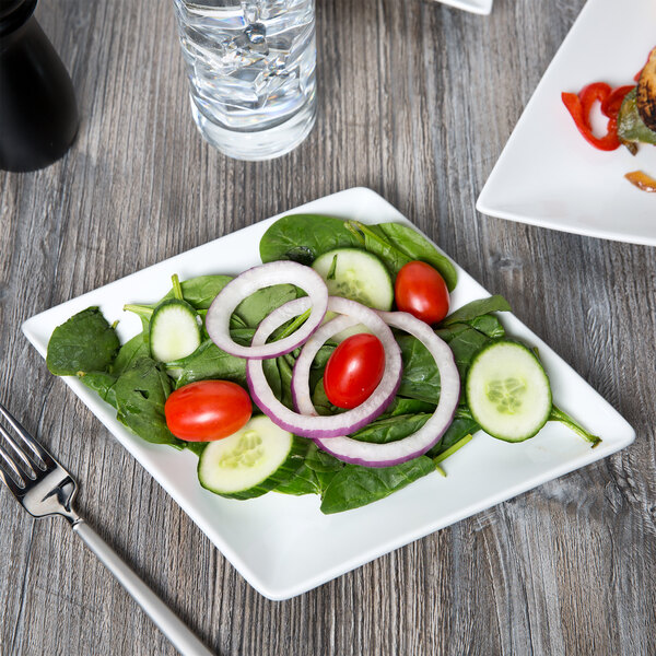 A CAC porcelain dinner plate with a salad on a table.